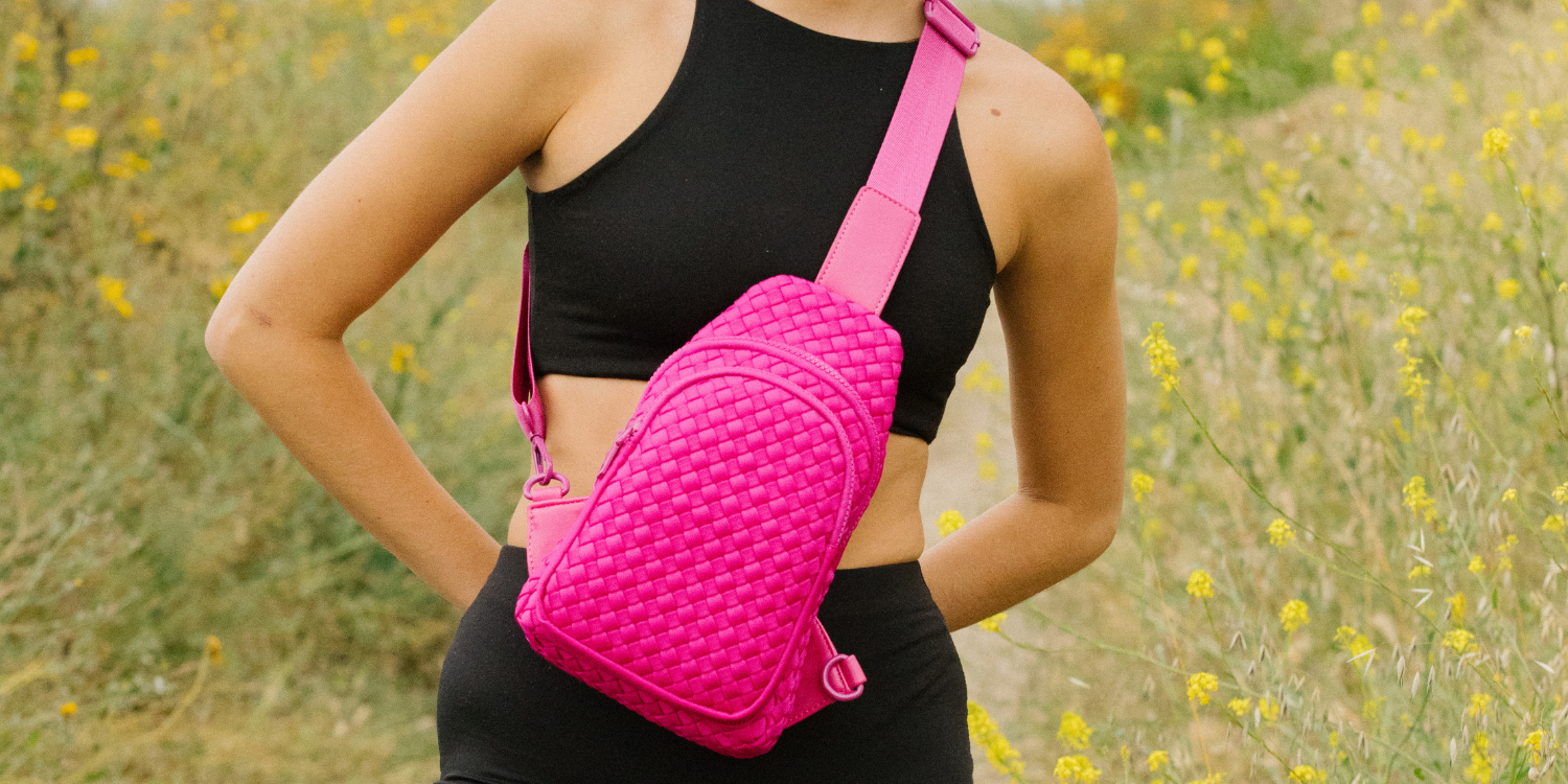 a woman in black activewear carrying a red sling backpack