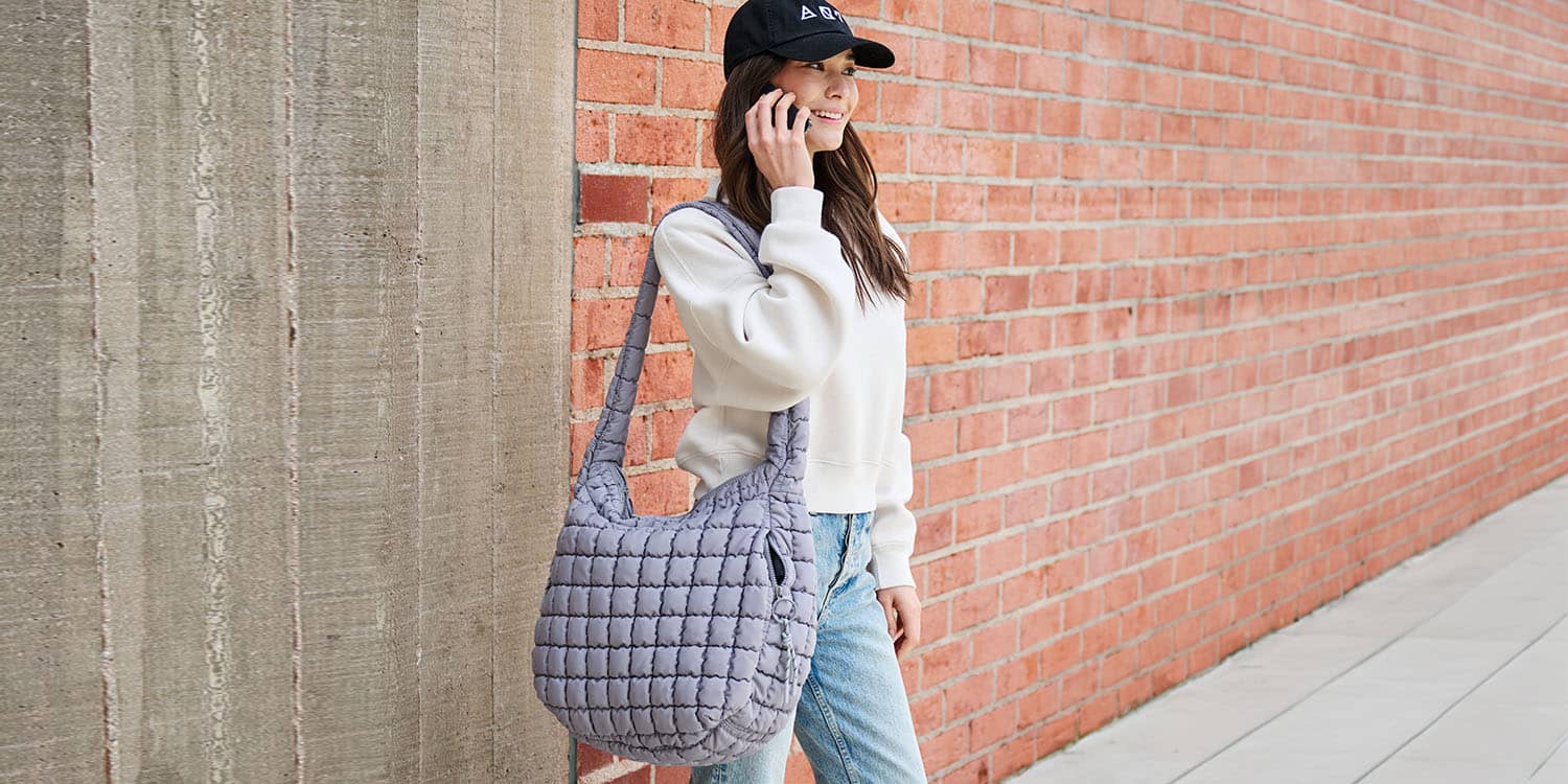 a model on the phone carrying a light purple bag