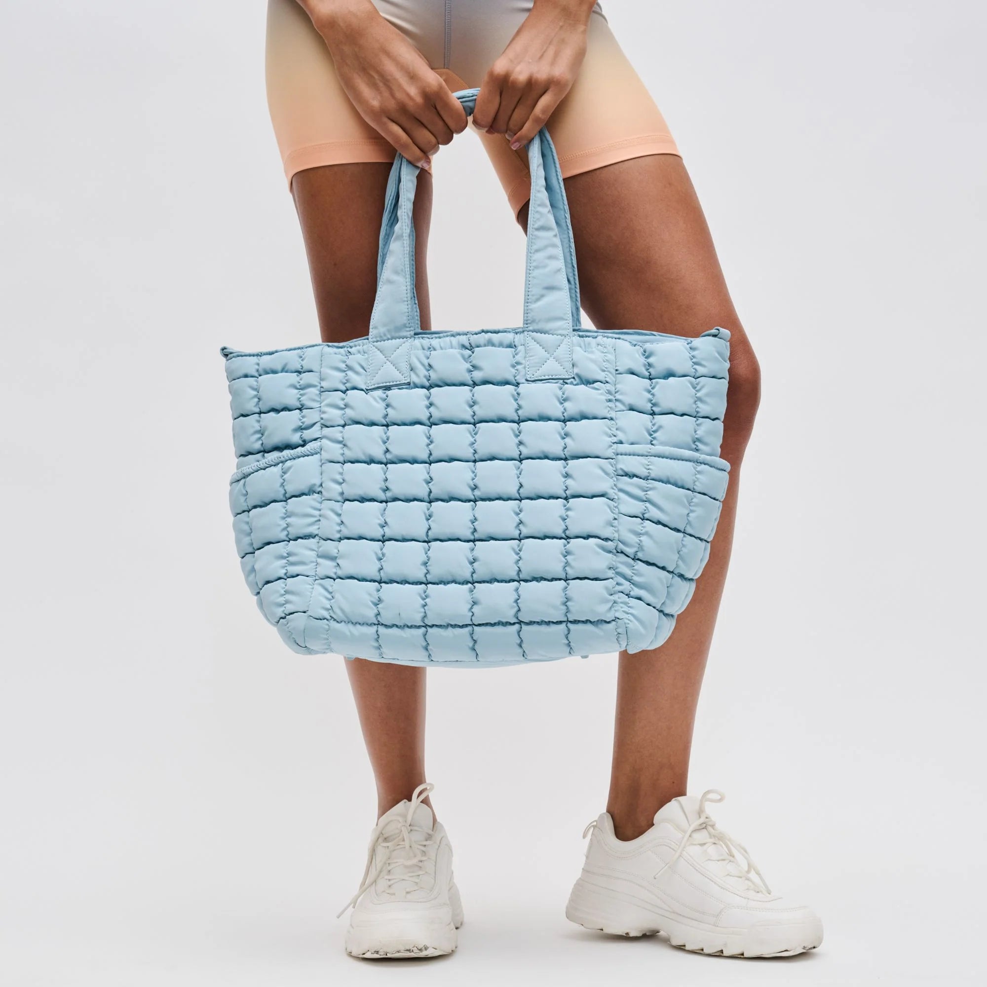 a model holding a blue quilted tote