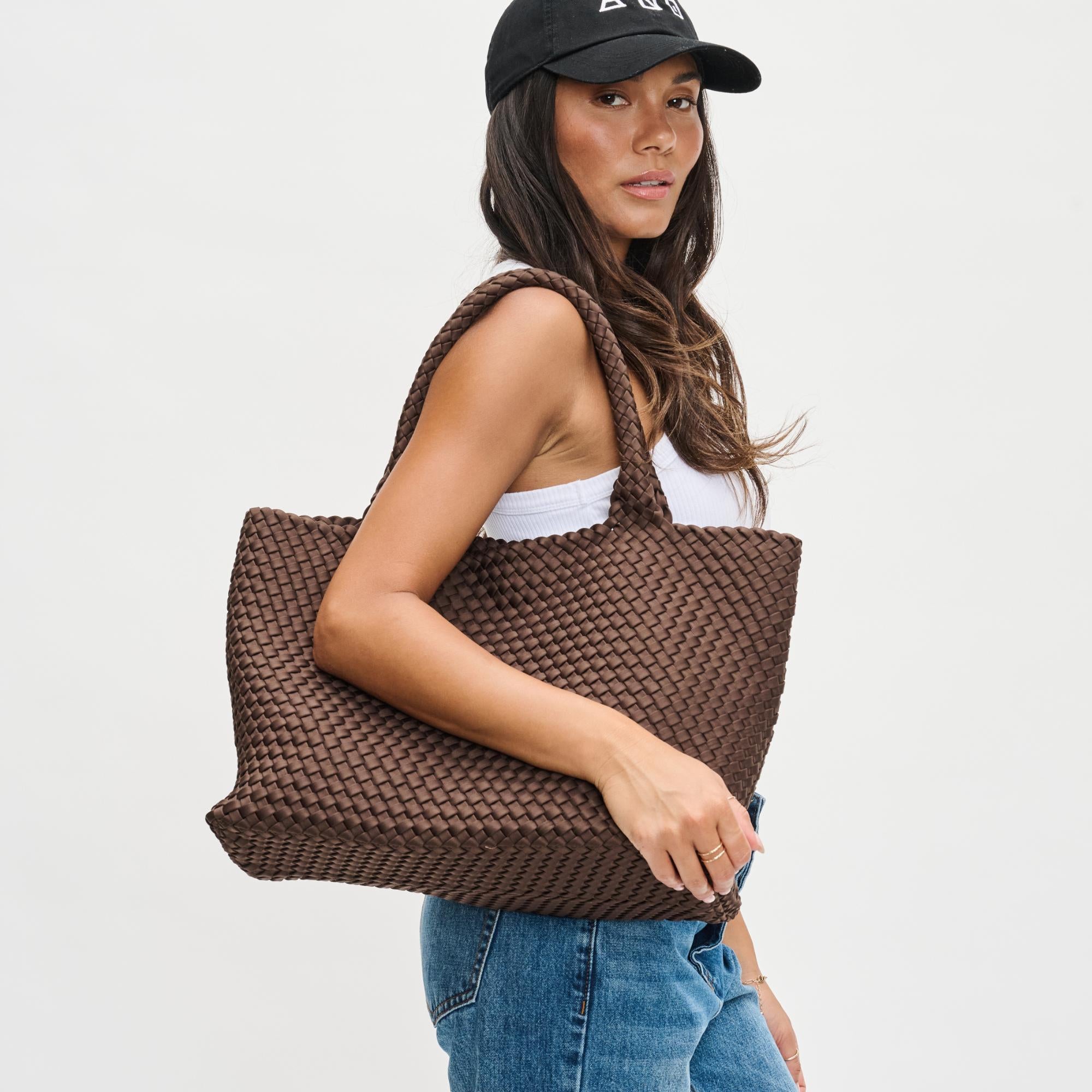 a model carrying a chocolate brown tote bag