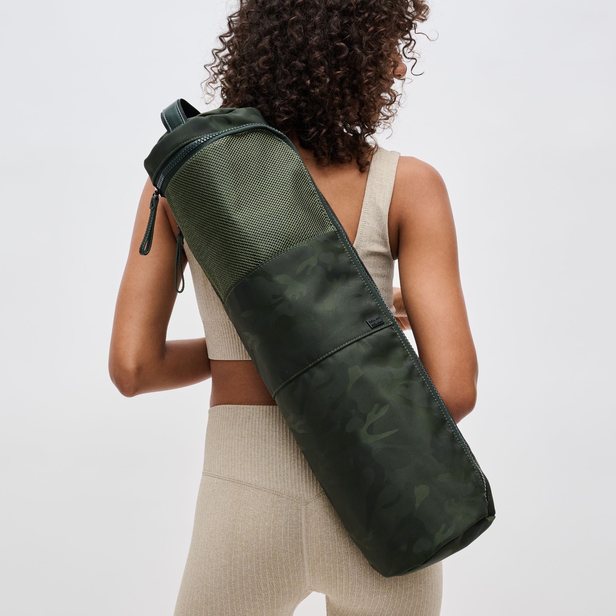 a model carrying a green camo yoga mat bag