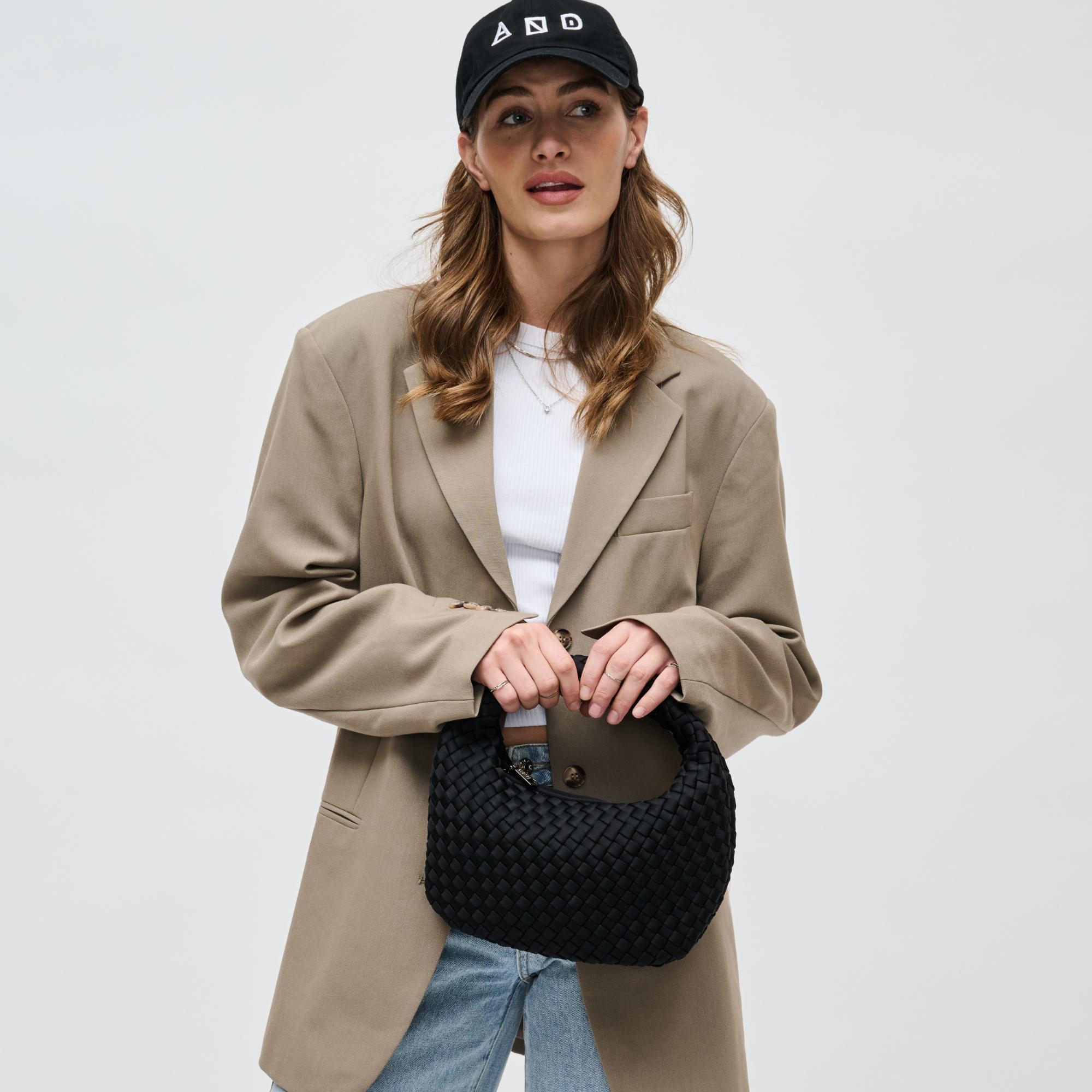 a model holding a black woven handbag