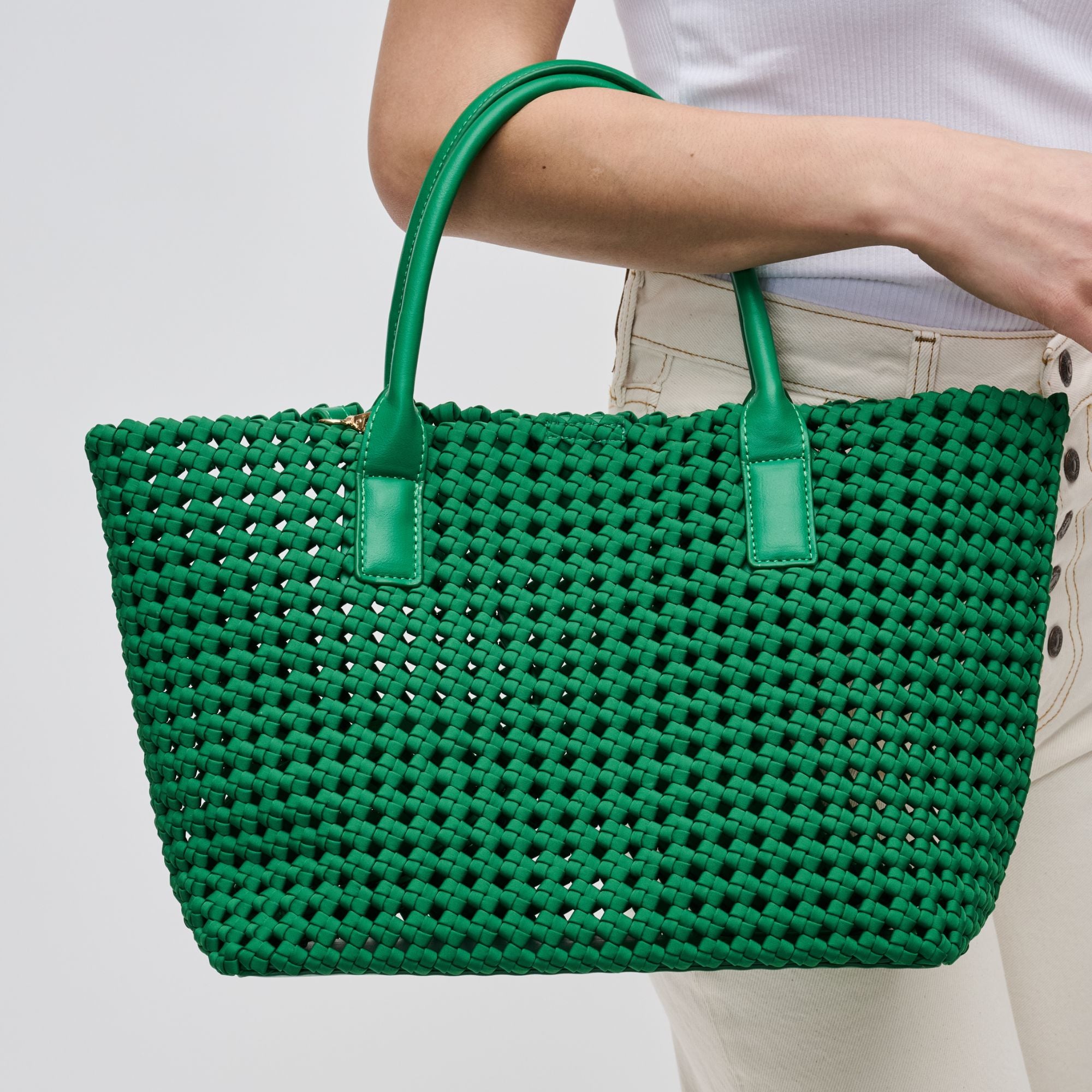 a model holding a green woven tote bag