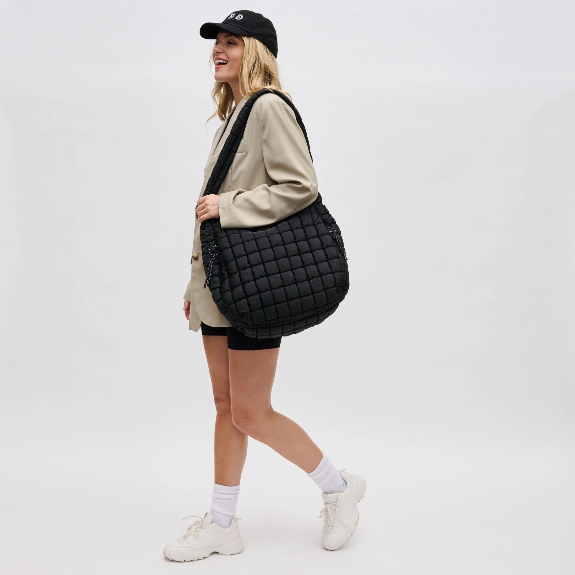 a model in a beige blazer carrying a large black tote bag