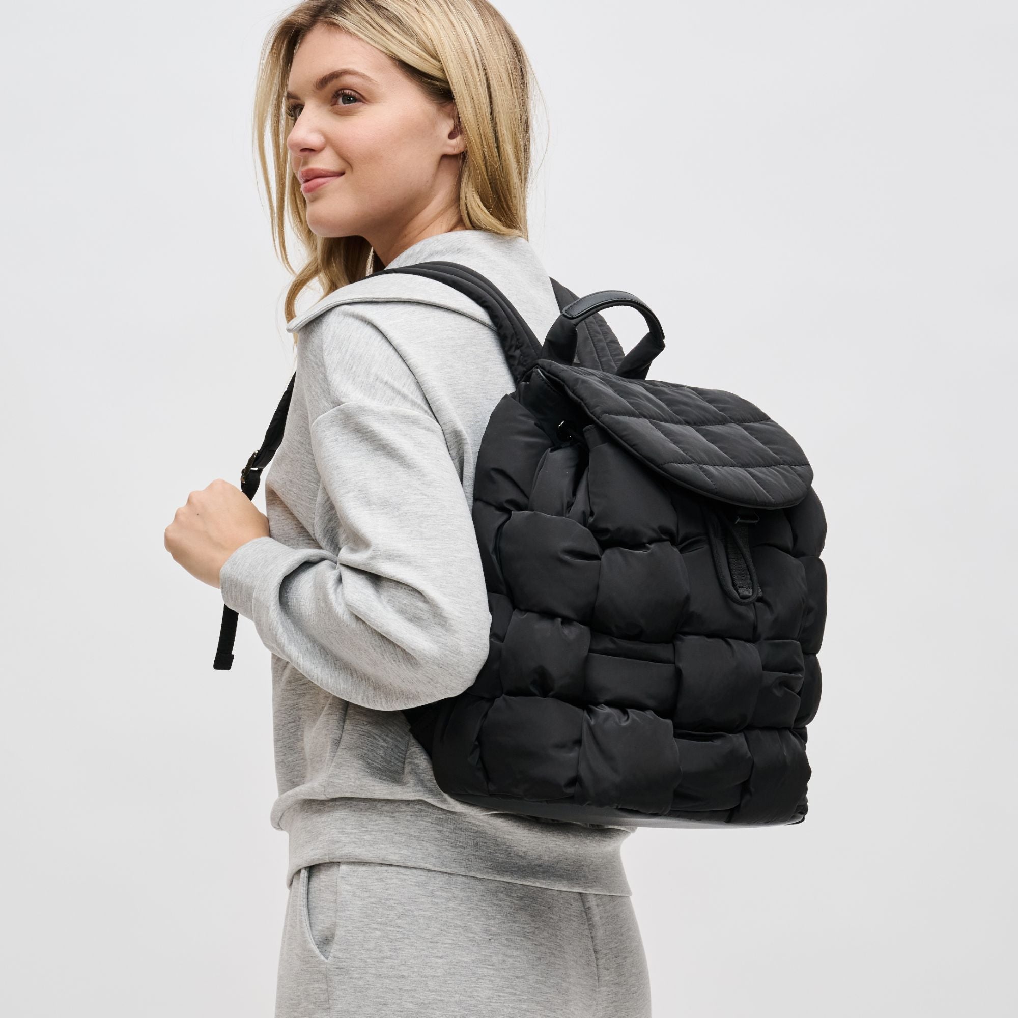 a model in a black puffer backpack and a gray sweater set
