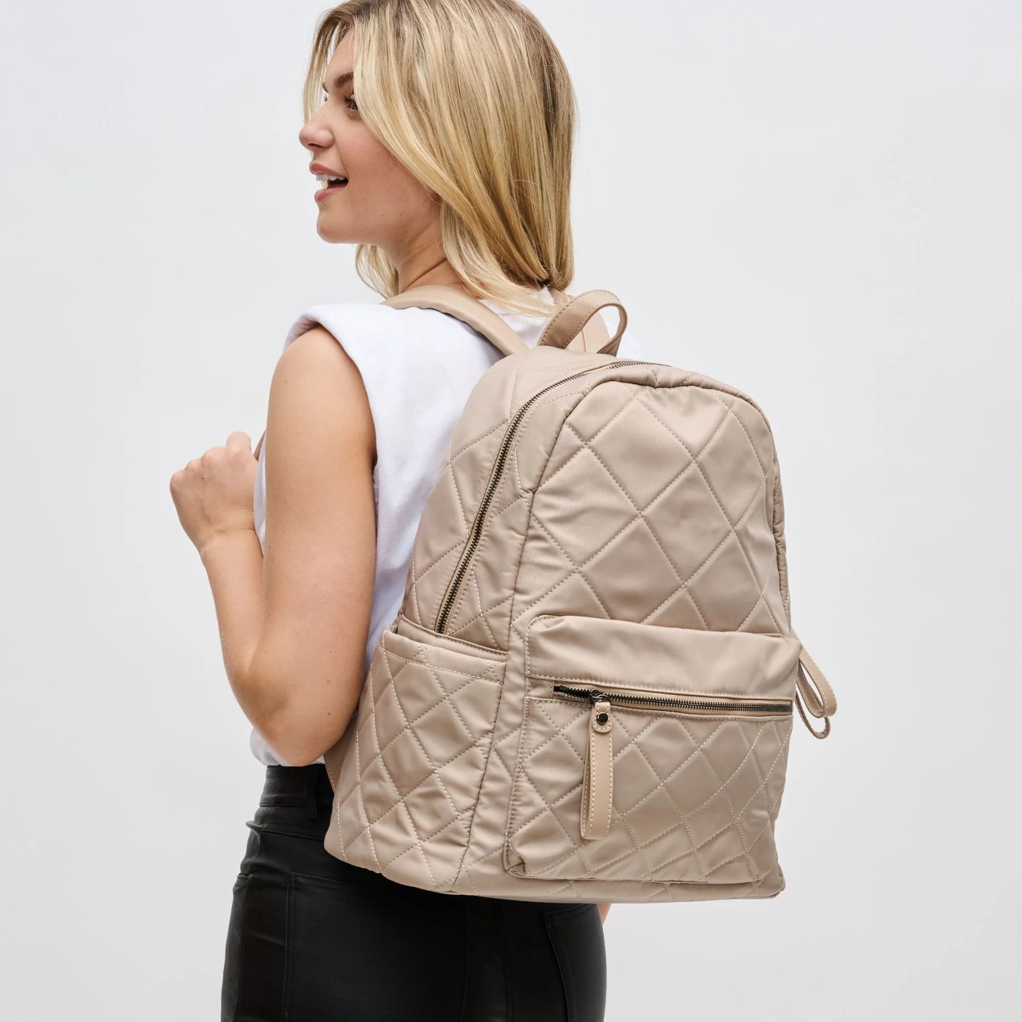 a model wearing a large nude colored backpack