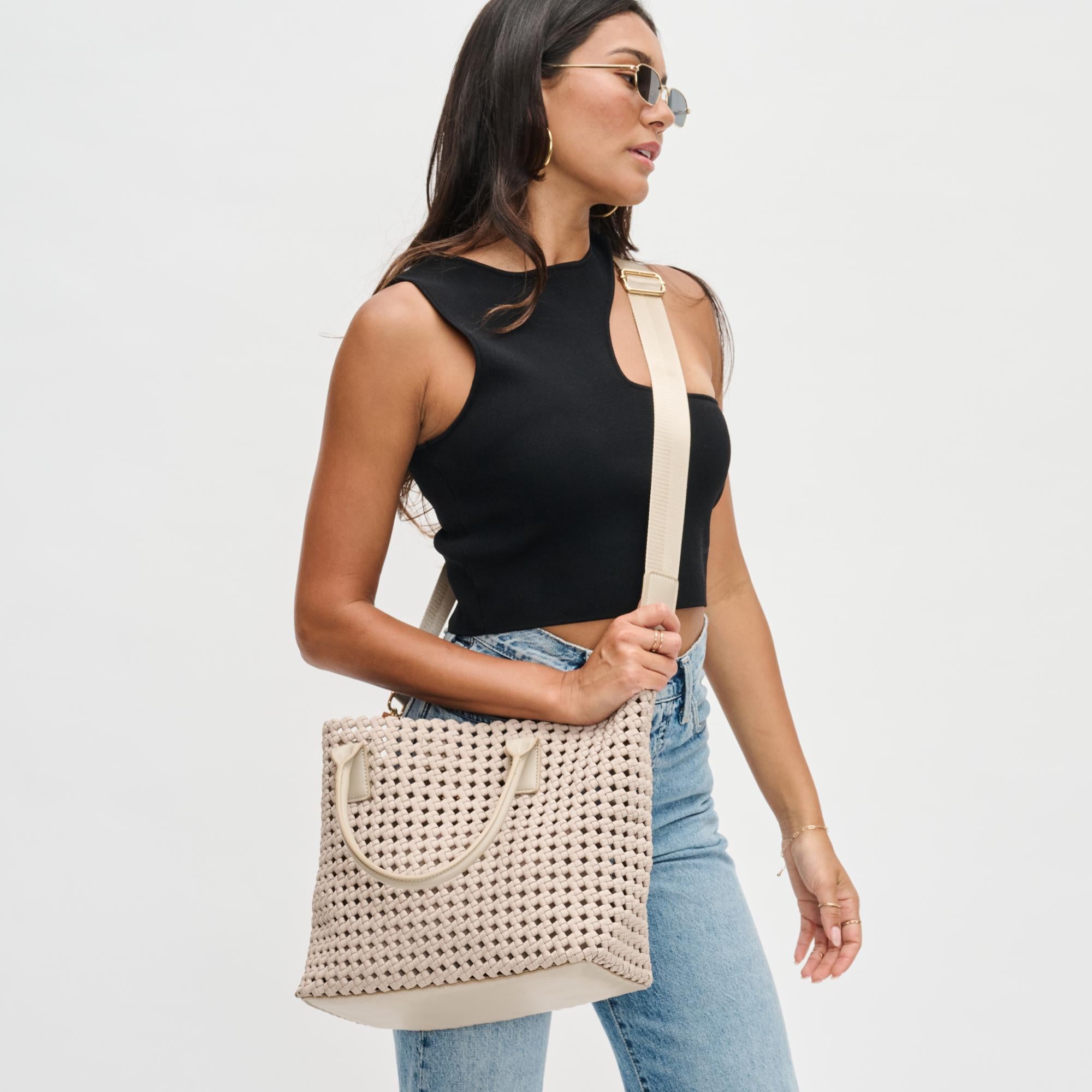 a model carrying a beige woven tote bag