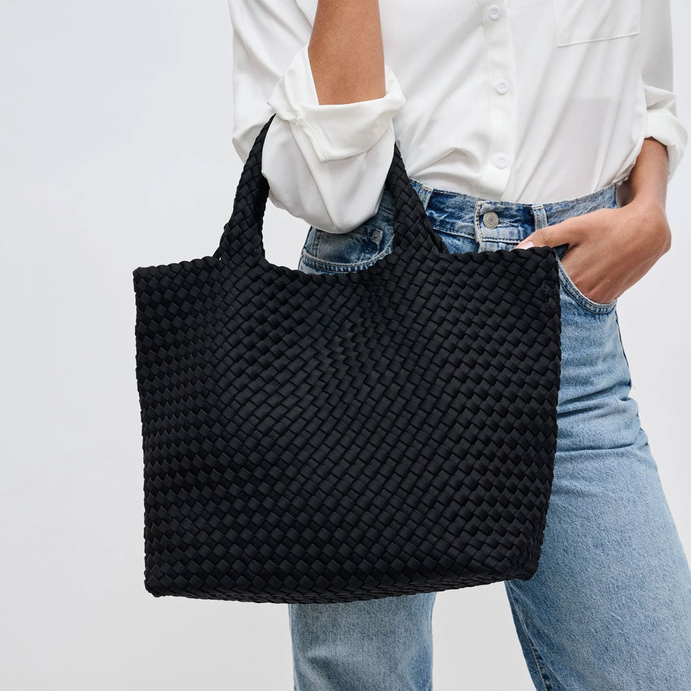 a model carrying a black woven tote