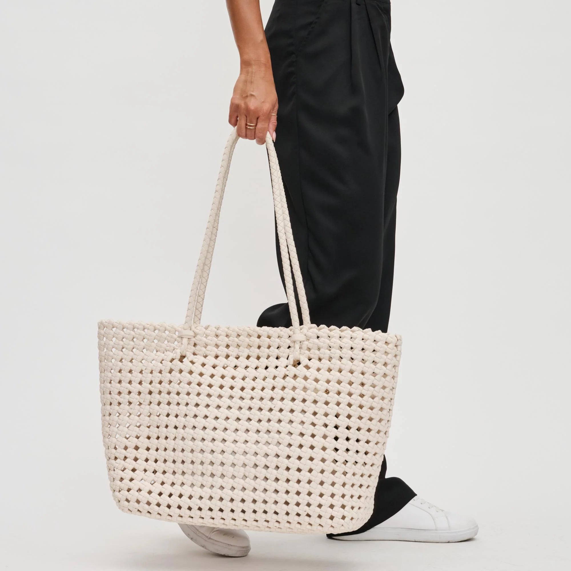 a model holding an ivory braided tote bag