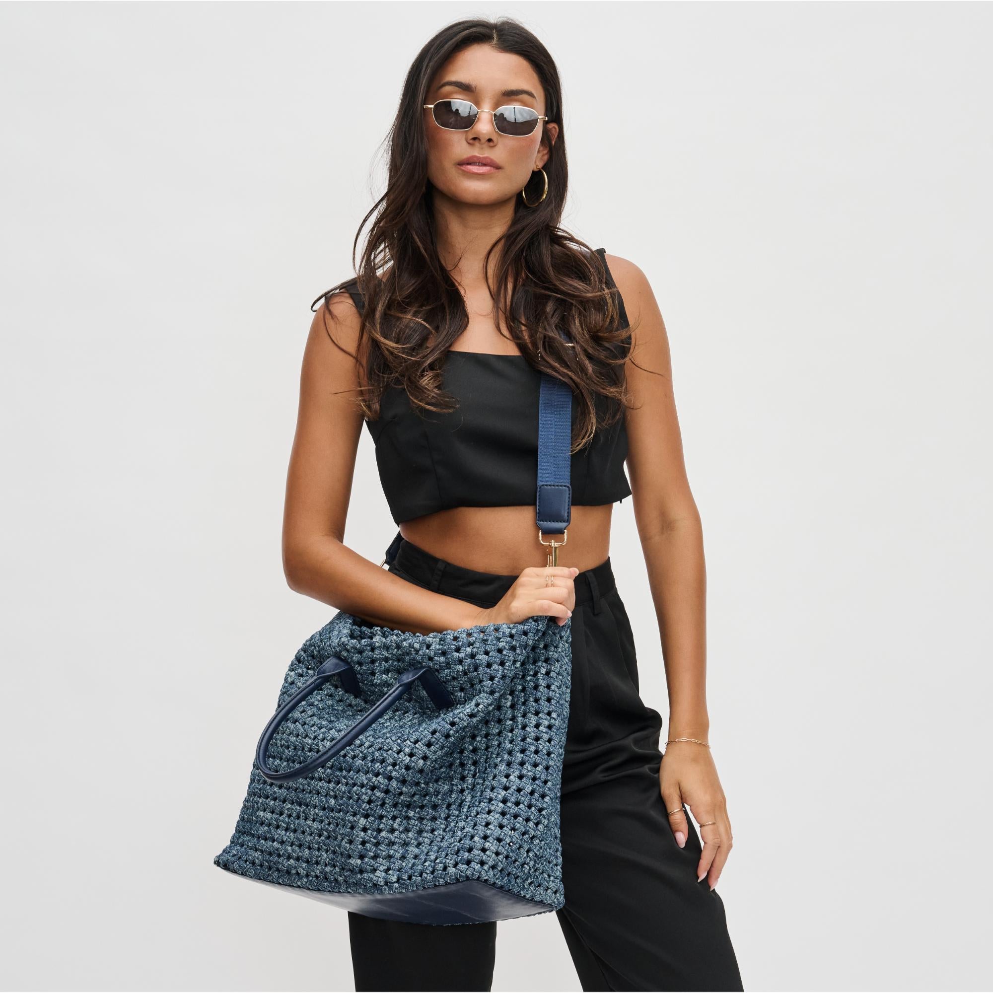 a model in sunglasses carrying a navy tote bag