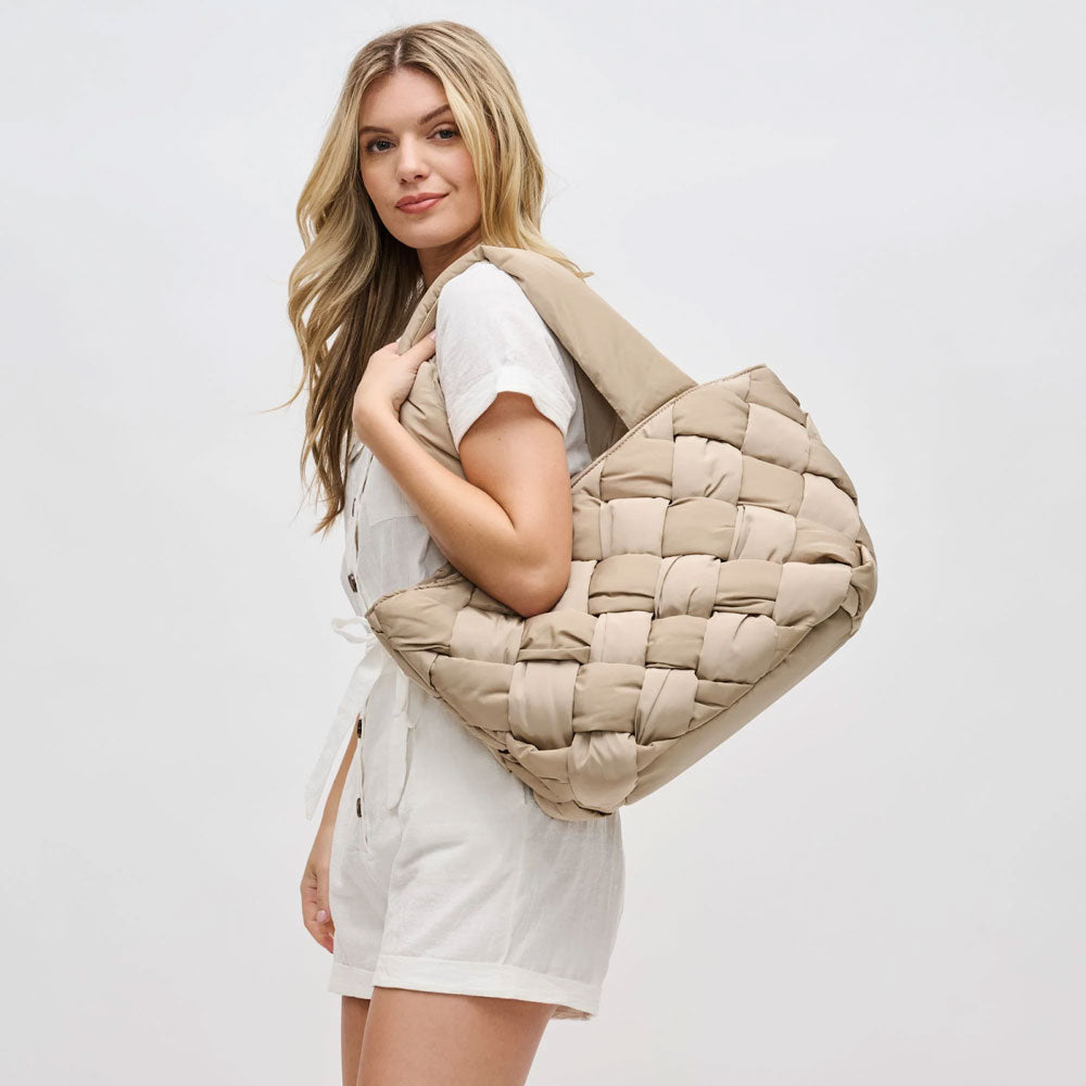 a model carrying a nude quilted tote bag