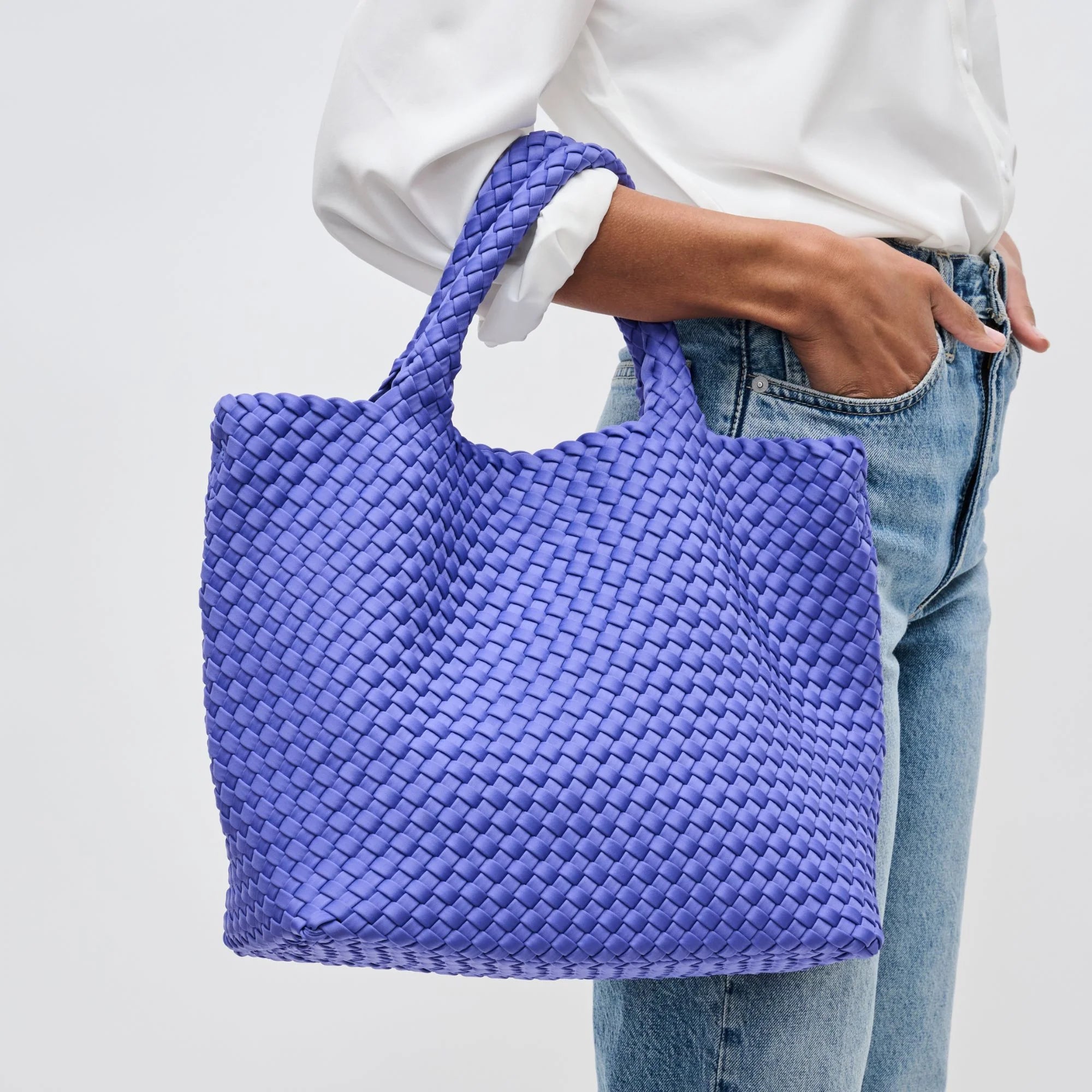a model holding a periwinkle woven tote bag
